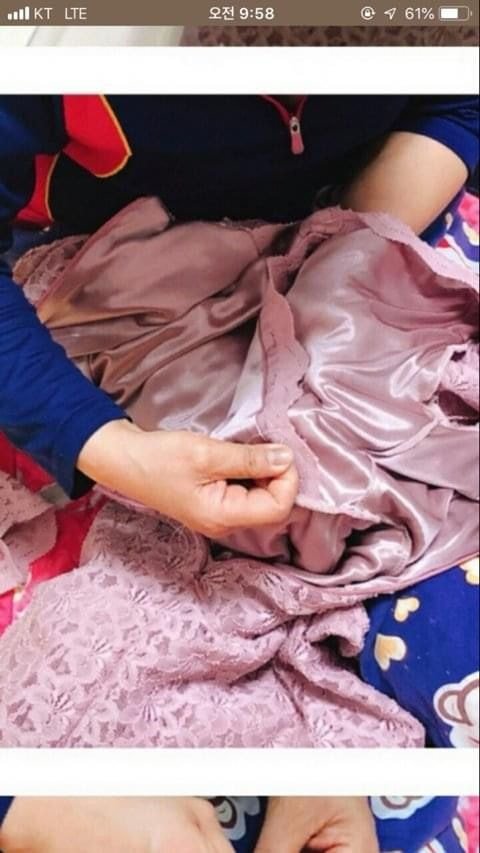Korean community post, image 2: Mom's hands, stitching a lining panel into the plunging neckline.